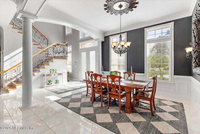 tiled dining space featuring ornate columns, crown molding, and a chandelier