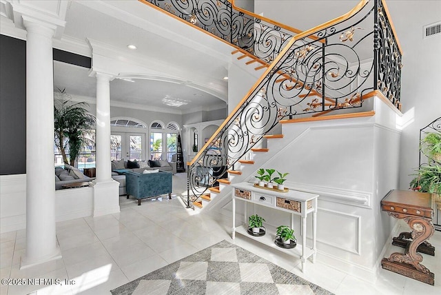 tiled foyer entrance with ornate columns, french doors, and ornamental molding