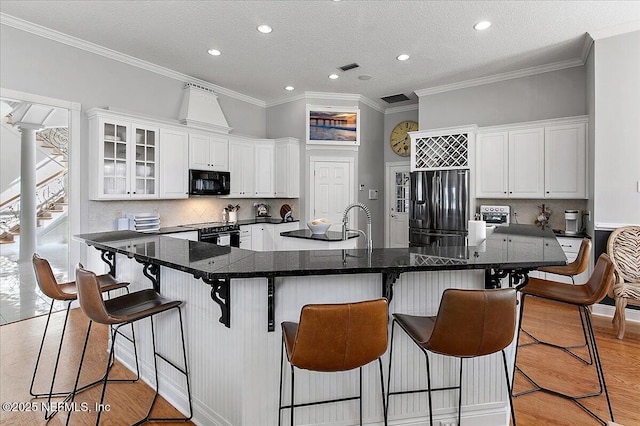 kitchen with white cabinetry, a breakfast bar, black appliances, and a textured ceiling