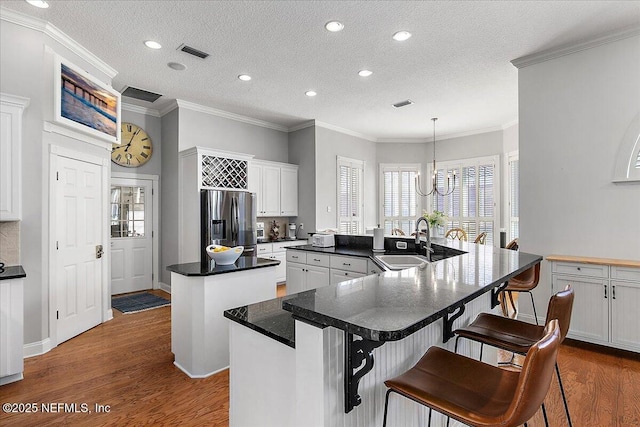 kitchen featuring stainless steel fridge, a center island, white cabinetry, and sink