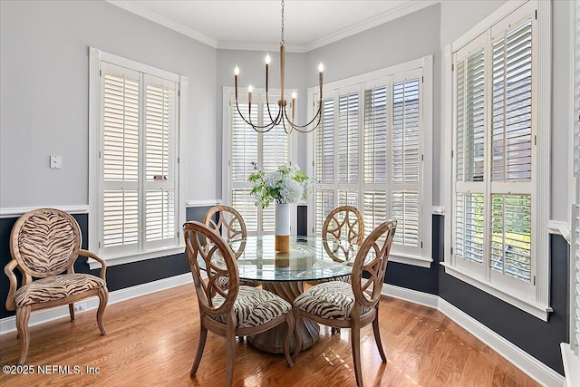 dining area with a chandelier, light wood-type flooring, and ornamental molding