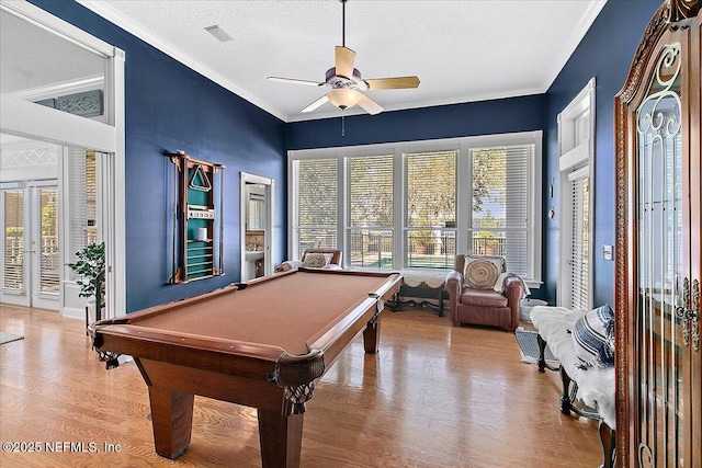 game room with a textured ceiling, ceiling fan, crown molding, light hardwood / wood-style floors, and pool table