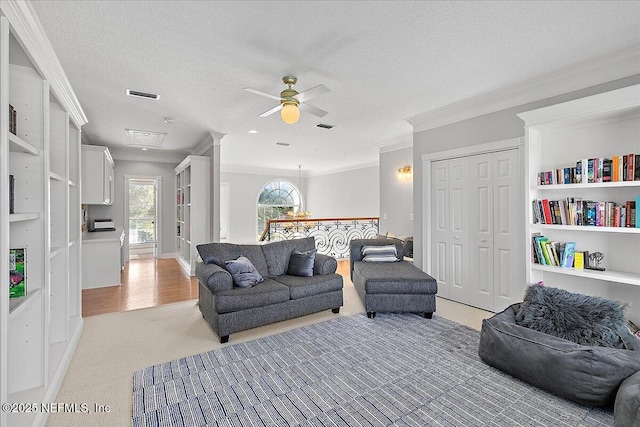 carpeted living room featuring crown molding, ceiling fan, and a textured ceiling