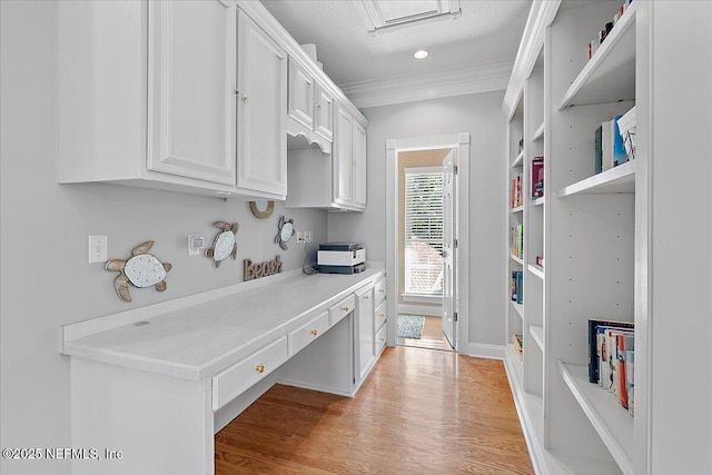 kitchen featuring white cabinets, light hardwood / wood-style floors, built in desk, and crown molding