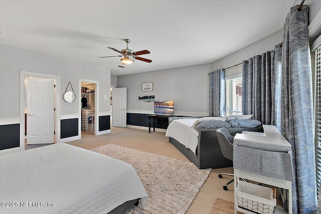 carpeted bedroom featuring ceiling fan, a spacious closet, a textured ceiling, and a closet