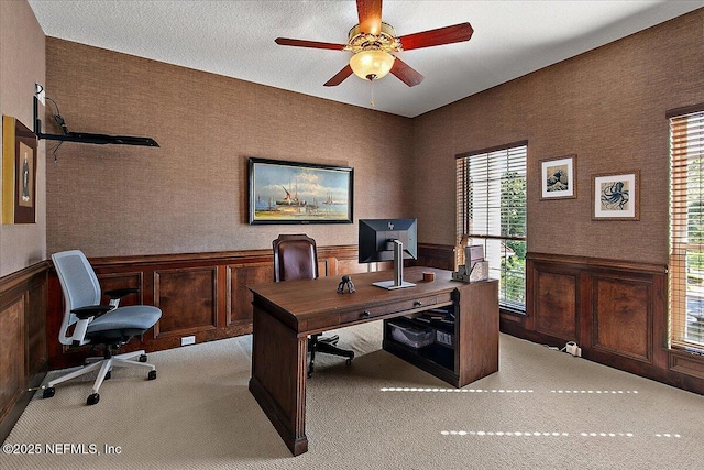 carpeted office space with ceiling fan