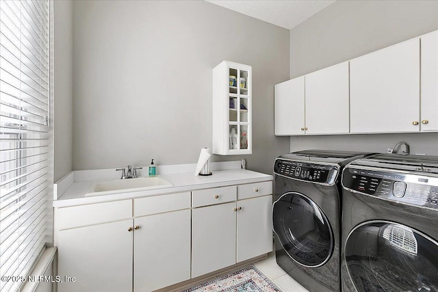 laundry room featuring cabinets, light tile patterned floors, washer and clothes dryer, and sink