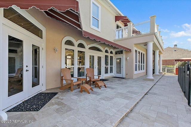 rear view of house with a patio area, a balcony, and french doors