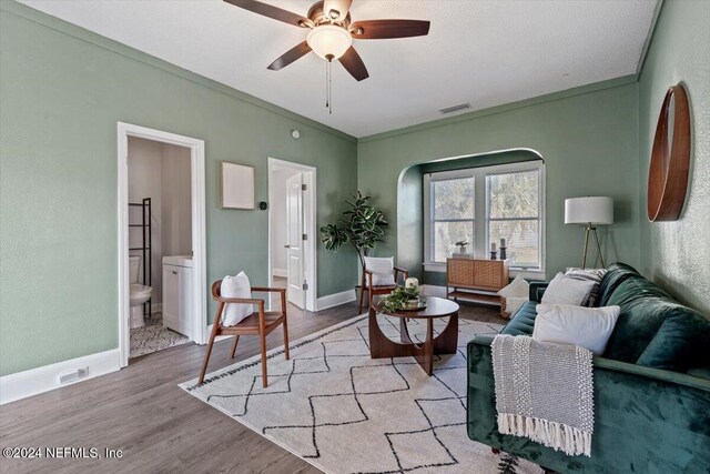 living room with ceiling fan, ornamental molding, and light hardwood / wood-style flooring