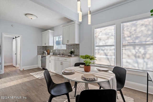 dining room with a textured ceiling, sink, light hardwood / wood-style floors, and plenty of natural light