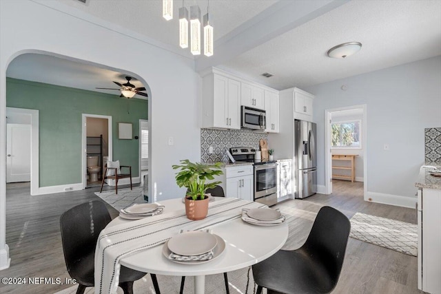 dining room featuring a textured ceiling, hardwood / wood-style floors, and ceiling fan with notable chandelier