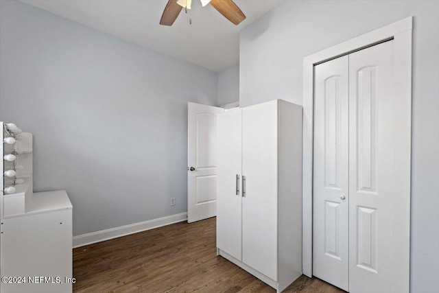 unfurnished bedroom with ceiling fan, a closet, and dark wood-type flooring