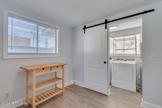 laundry area featuring a barn door, light wood-type flooring, and washer / dryer