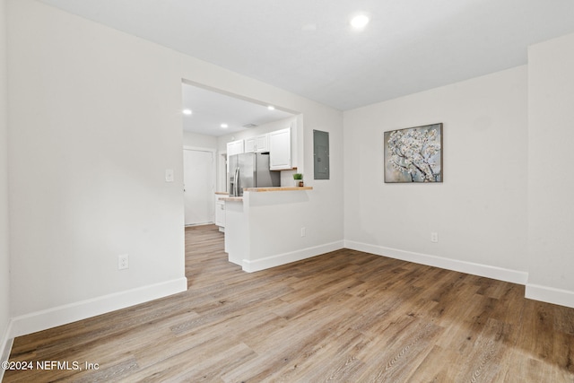 spare room featuring electric panel and light wood-type flooring