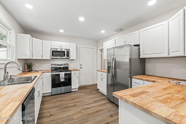 kitchen featuring white cabinets, sink, stainless steel appliances, and wooden counters