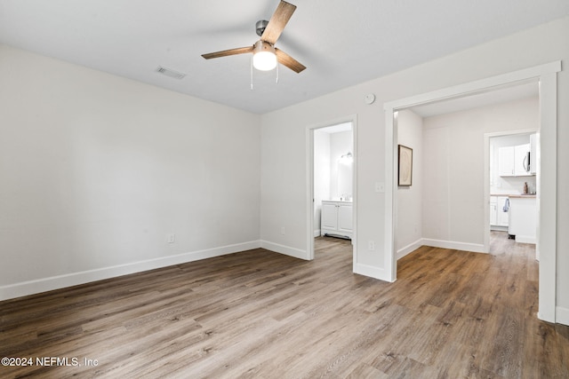 unfurnished bedroom featuring ensuite bath, ceiling fan, and light hardwood / wood-style floors