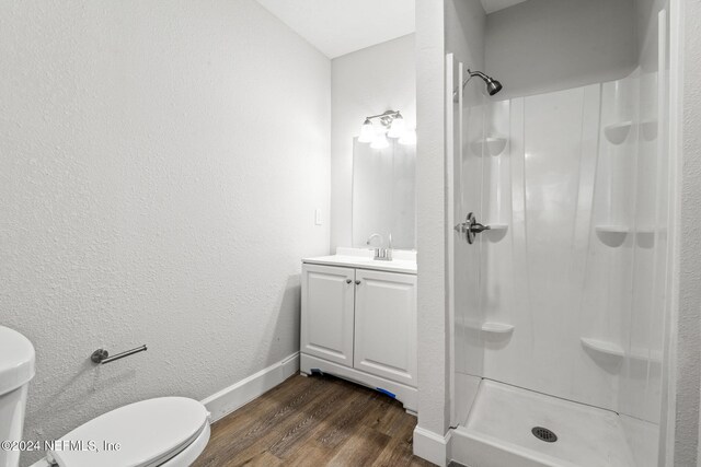 bathroom with a shower, hardwood / wood-style floors, vanity, and toilet