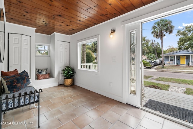 entryway with ornamental molding and wood ceiling