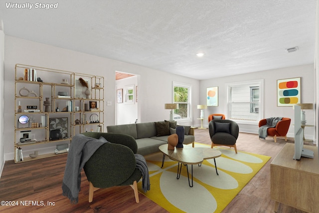 living room with a textured ceiling and dark hardwood / wood-style floors