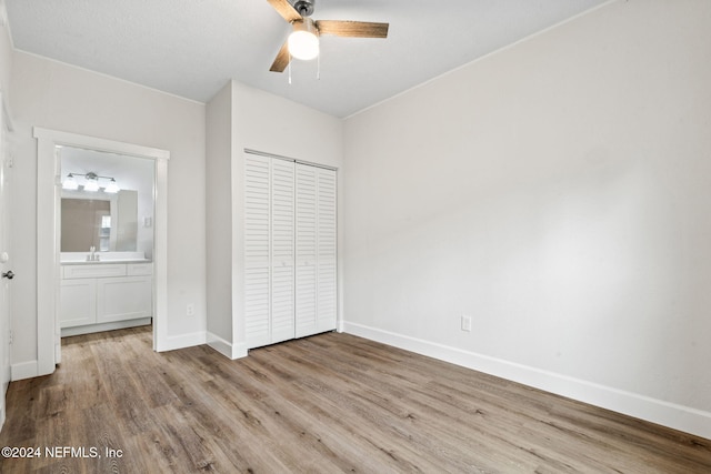 unfurnished bedroom with ceiling fan, sink, light hardwood / wood-style flooring, ensuite bathroom, and a closet