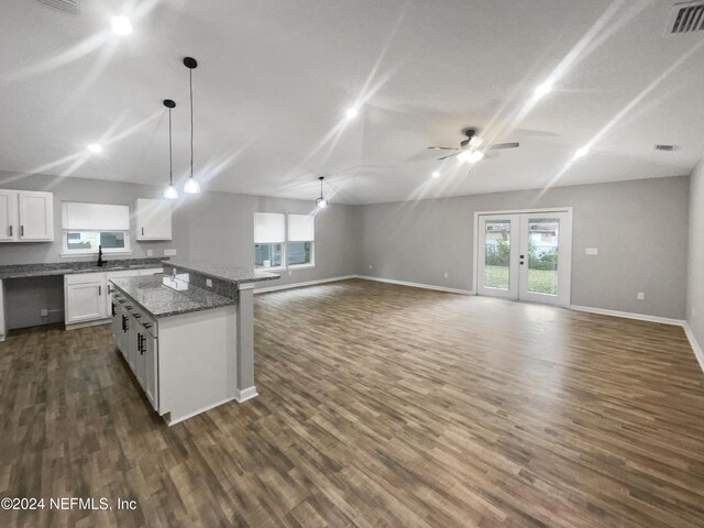 kitchen with white cabinets, sink, hanging light fixtures, stone countertops, and a kitchen island