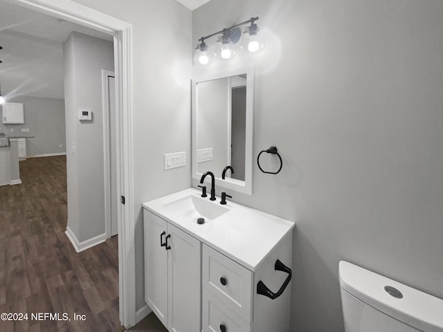 bathroom with toilet, vanity, and hardwood / wood-style flooring