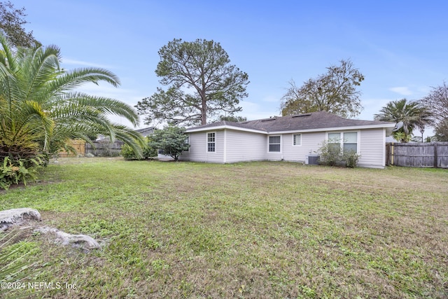 back of property with a lawn and cooling unit