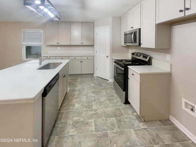 kitchen featuring a textured ceiling, stainless steel appliances, a kitchen island with sink, sink, and white cabinets