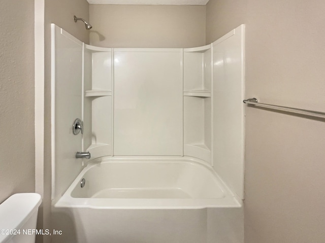 bathroom with a textured ceiling, shower / bathtub combination, and toilet