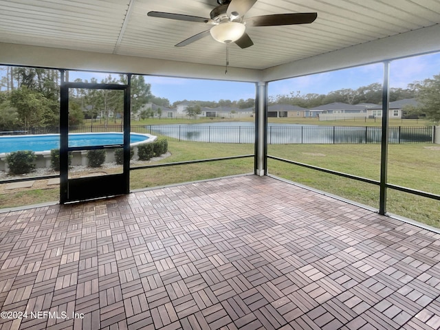 unfurnished sunroom featuring ceiling fan and a water view