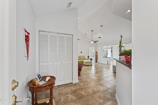 hallway with tile patterned floors and high vaulted ceiling