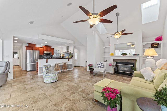 living room featuring ceiling fan, built in features, high vaulted ceiling, and a skylight