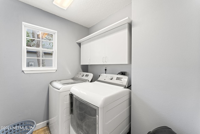 laundry area with washer and clothes dryer, cabinets, and a textured ceiling