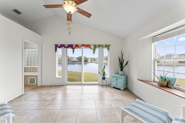 unfurnished room with a water view, vaulted ceiling, ceiling fan, and light tile patterned flooring