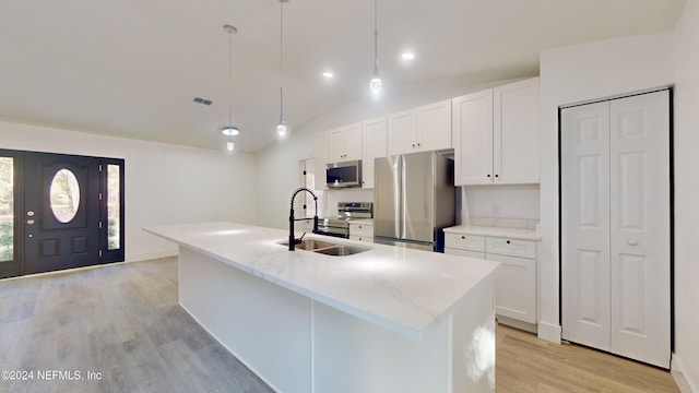 4774 Leopard Cir, Middleburg, FL 32068 - kitchen featuring appliances with stainless steel finishes, light wood-style floors, white cabinetry, lofted ceiling, and an island with sink