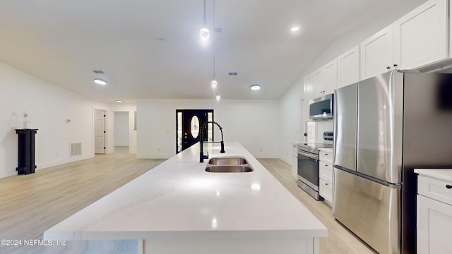 kitchen with white cabinetry, an island with sink, appliances with stainless steel finishes, and decorative light fixtures