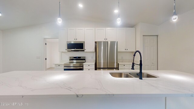4774 Leopard Cir, Middleburg, FL 32068 - kitchen with stainless steel appliances, vaulted ceiling, white cabinetry, decorative light fixtures, and light stone countertops