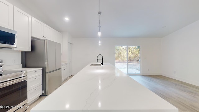 kitchen featuring white cabinetry, appliances with stainless steel finishes, sink, and hanging light fixtures