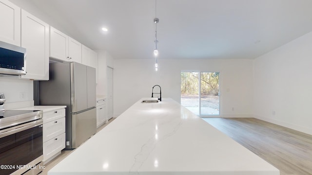 4774 Leopard Cir, Middleburg, FL 32068 - kitchen featuring appliances with stainless steel finishes, a center island with sink, white cabinets, light wood-style flooring, and recessed lighting