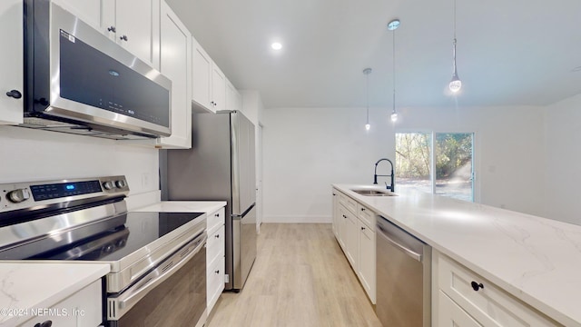 kitchen featuring sink, stainless steel appliances, light stone countertops, white cabinets, and decorative light fixtures