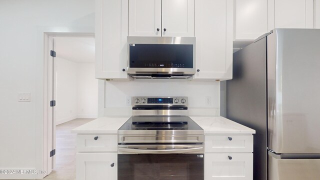 4774 Leopard Cir, Middleburg, FL 32068 - kitchen featuring stainless steel appliances, white cabinets, light stone counters, and light wood finished floors