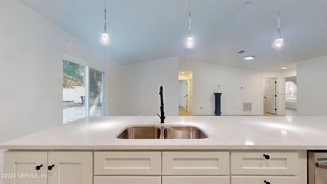 kitchen featuring sink, white cabinetry, vaulted ceiling, hanging light fixtures, and light stone countertops