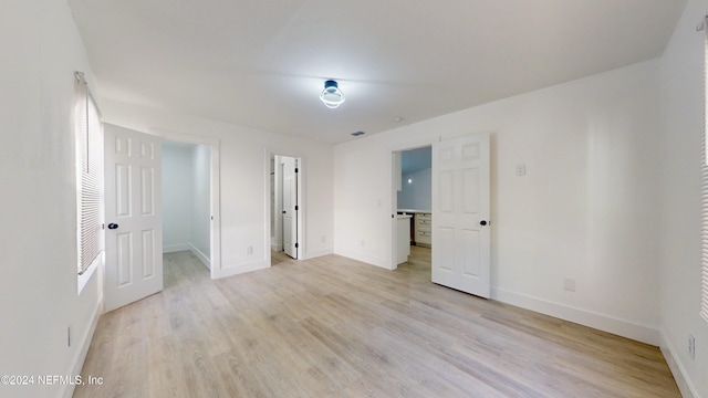 unfurnished bedroom featuring a walk in closet and light hardwood / wood-style flooring