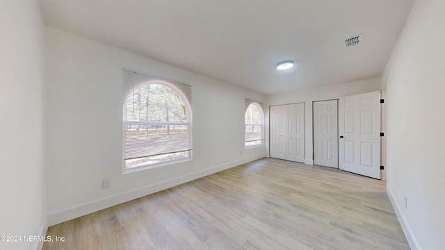 unfurnished bedroom featuring two closets and light wood-type flooring