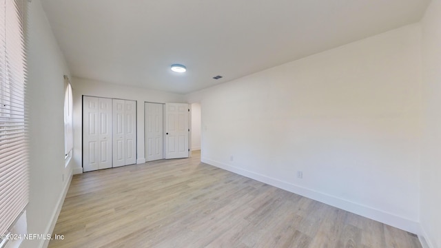 unfurnished bedroom featuring two closets and light hardwood / wood-style floors