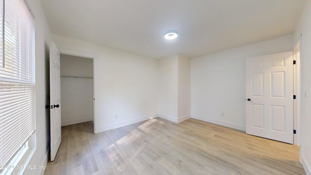 unfurnished bedroom with a walk in closet and light wood-type flooring