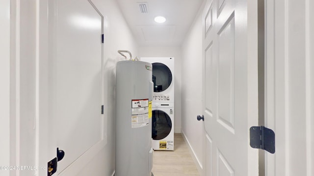 interior space with stacked washer / drying machine, light hardwood / wood-style flooring, and electric water heater