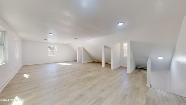 additional living space featuring vaulted ceiling and light wood-type flooring