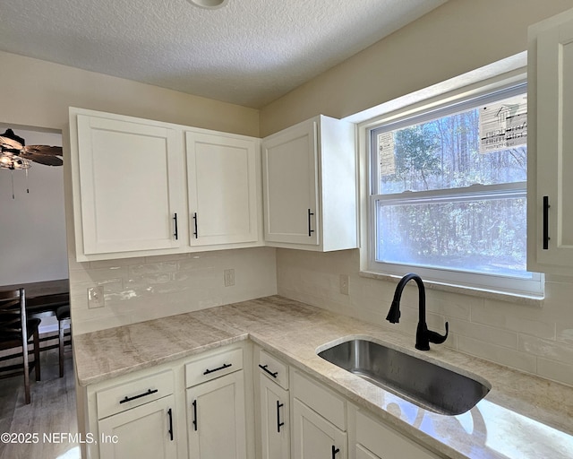 kitchen featuring white cabinets, sink, and a textured ceiling