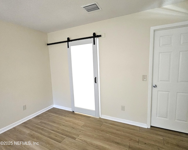 spare room with hardwood / wood-style flooring and a barn door